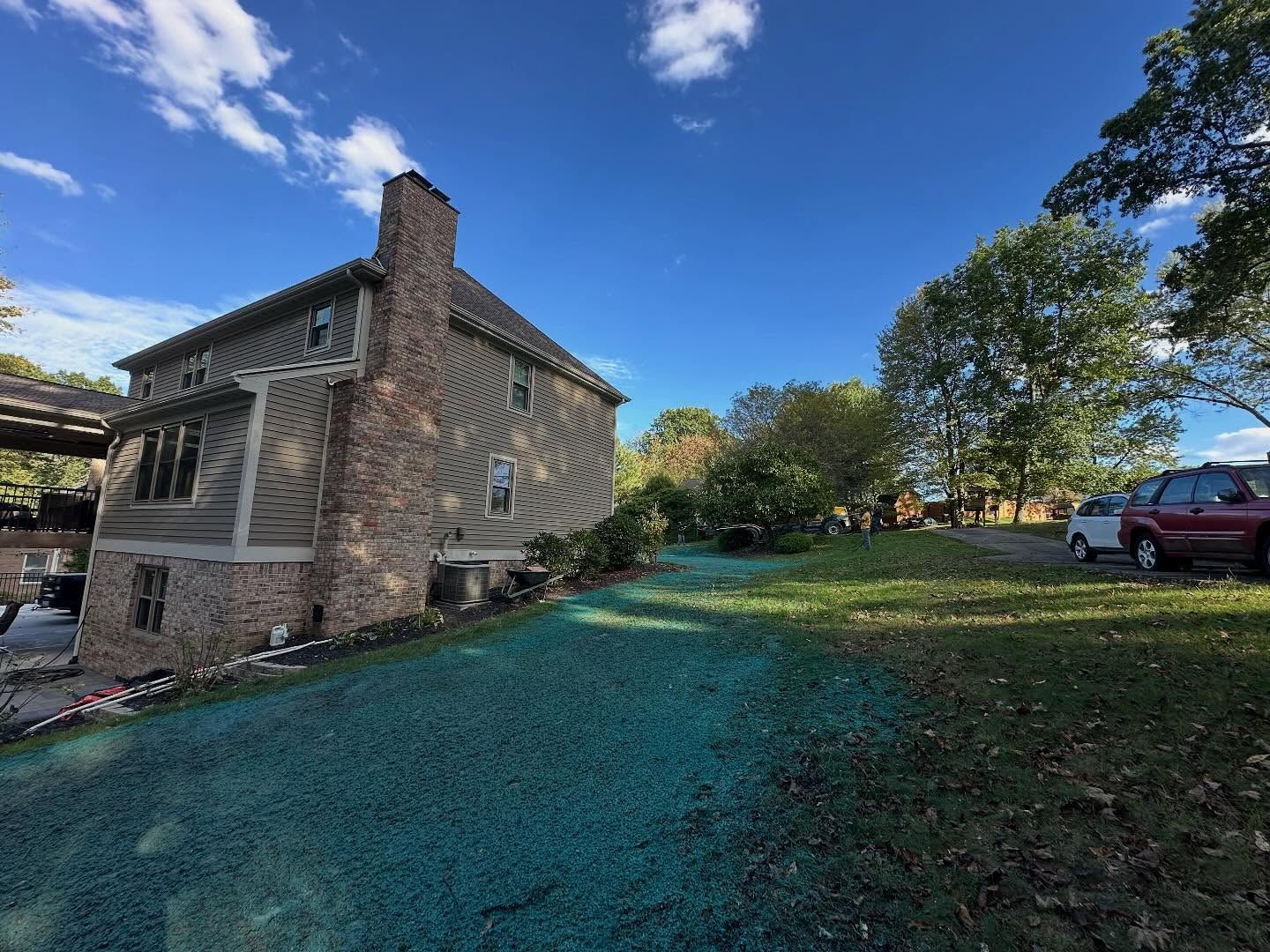 Stone house beside a grassy yard under a blue sky, with a red truck parked nearby
