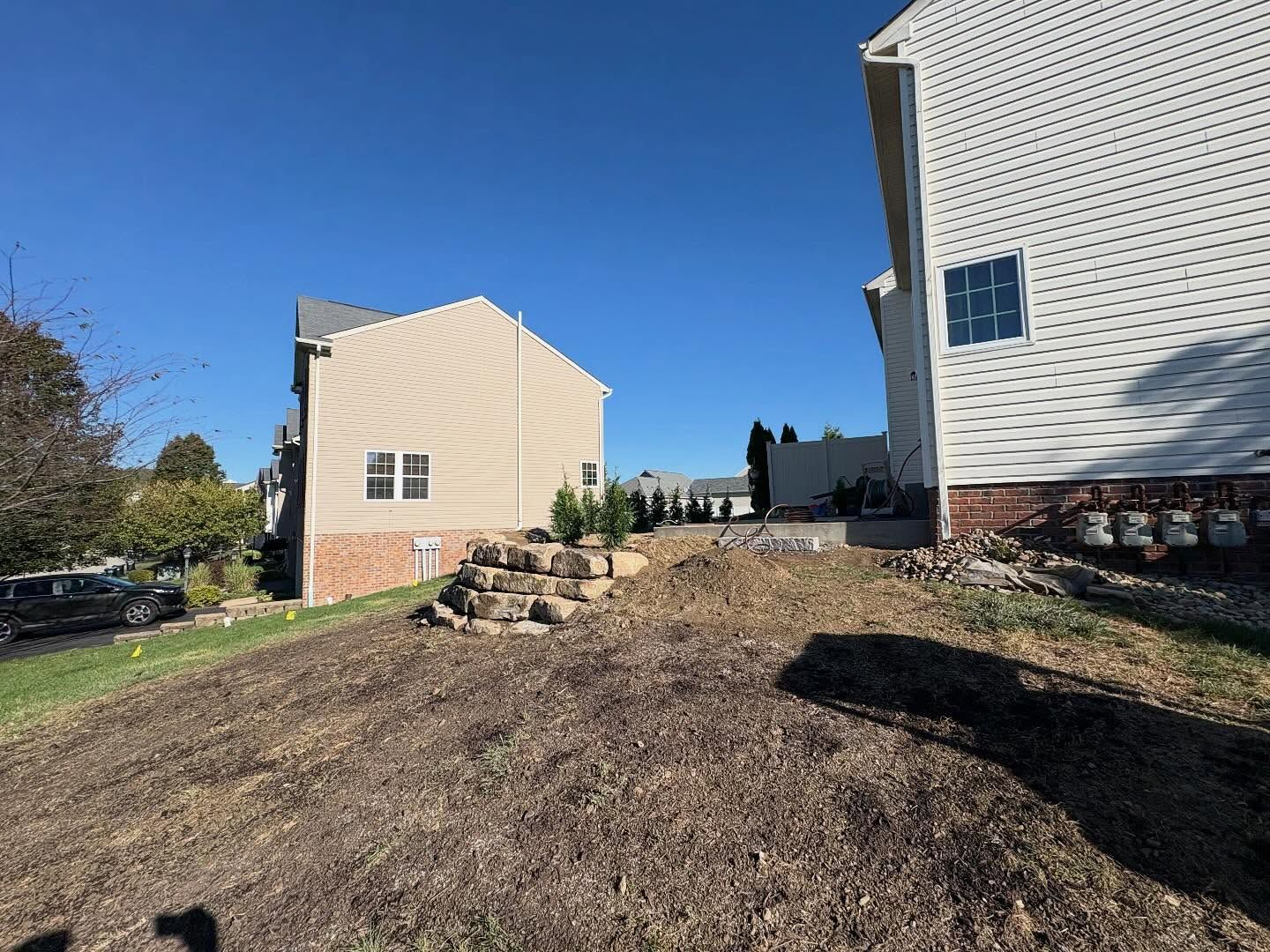 Apartment buildings with a grassy slope, stone retaining wall, and clear blue sky