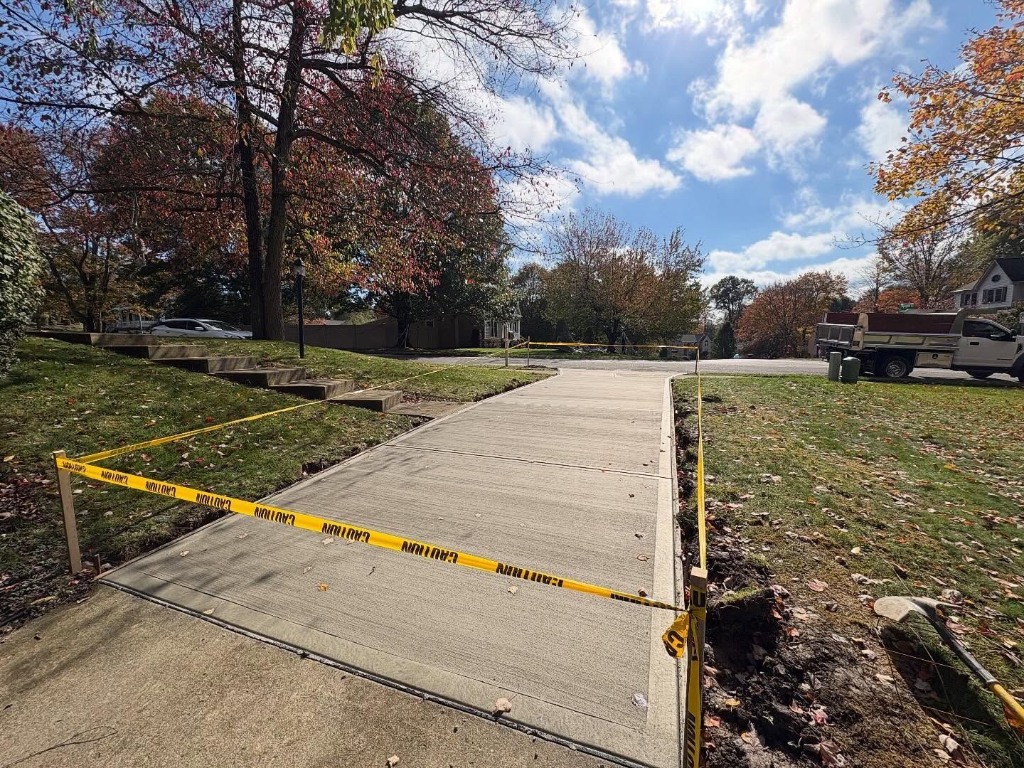 Blocked sidewalk ramp with caution tape across a concrete path in a residential neighborhood.