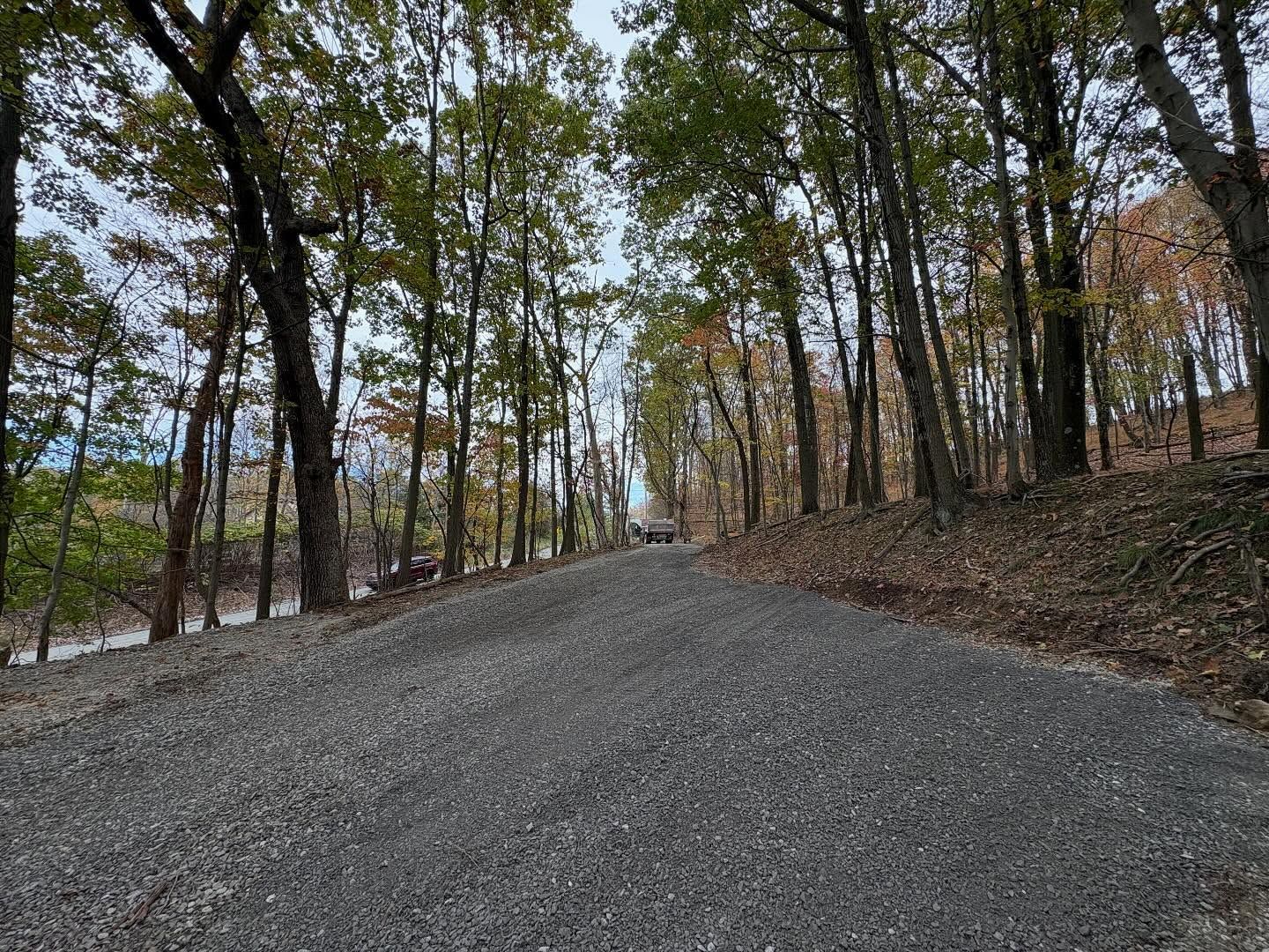 Gravel road winding uphill through leafless trees in a quiet wooded area