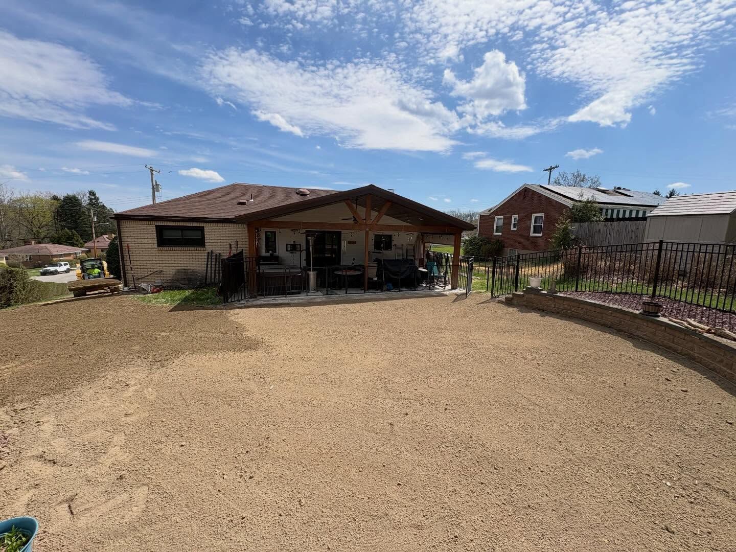 Gravel driveway leading to a single-story house with a covered porch under a partly cloudy sky.
