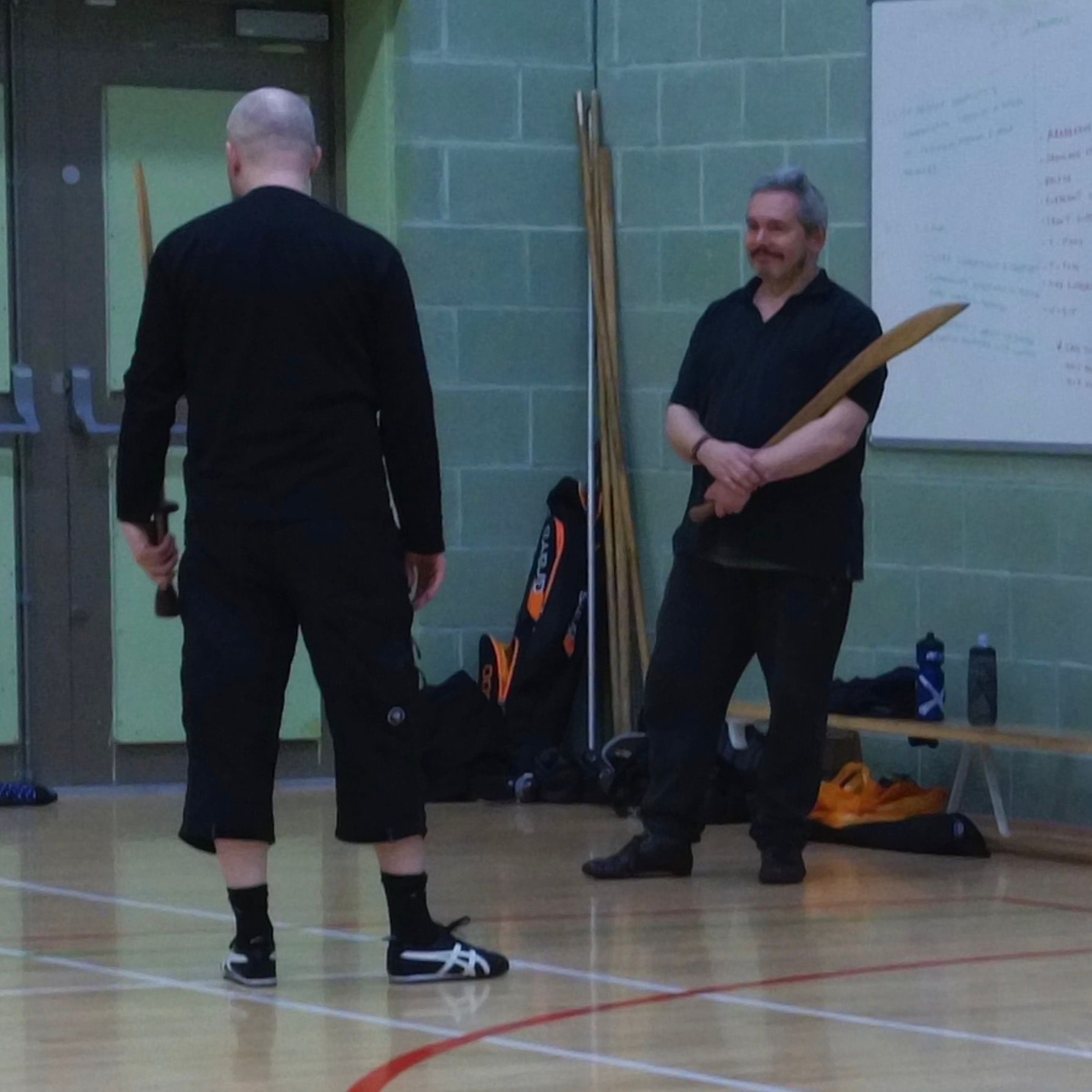 Two men standing on a gym floor holding Sabres Wudang Tai Chi Chuan Sabre Form