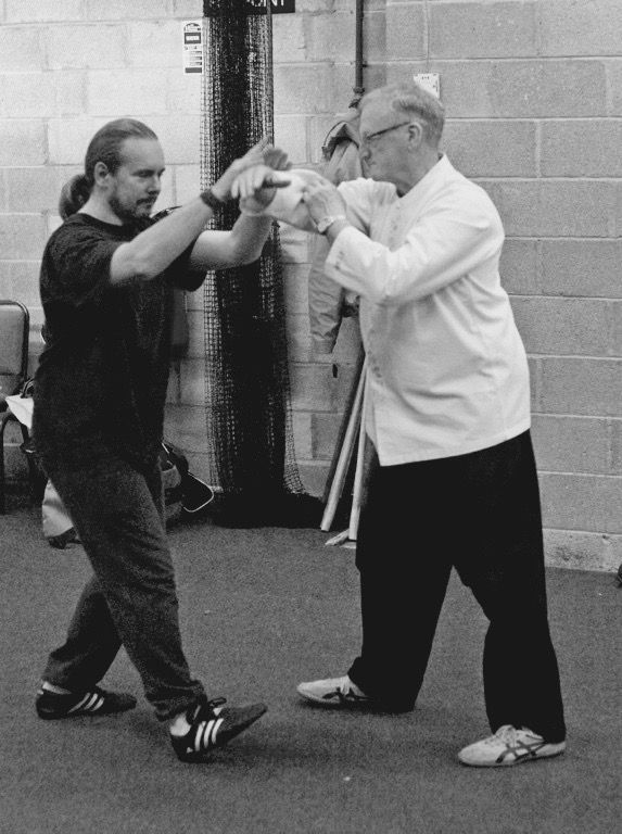 A black and white photo of two men practicing martial arts tai Chi Chuan Pushing hands