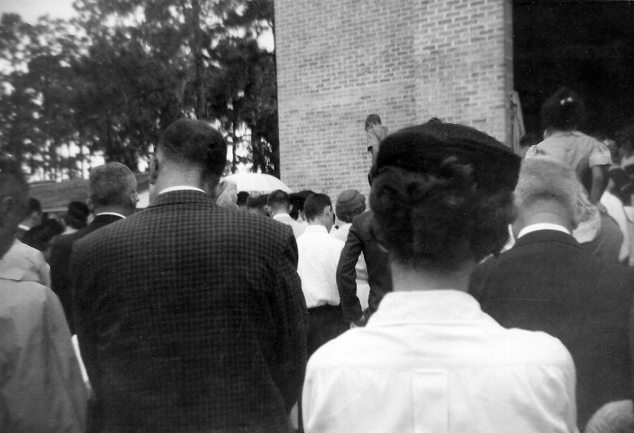 People gathered near a tall brick structure, likely an outdoor event.
