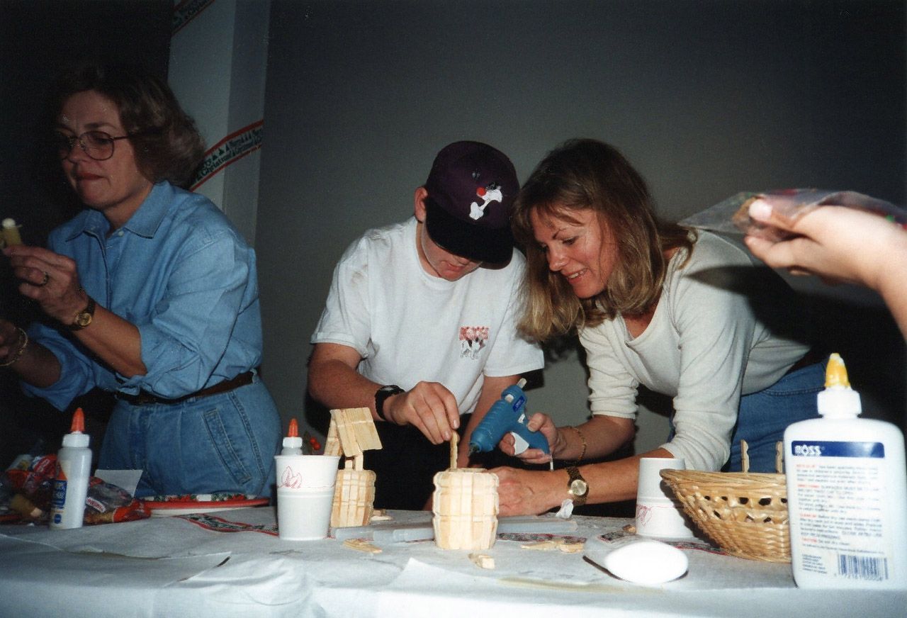 People crafting at a table with glue guns and supplies.