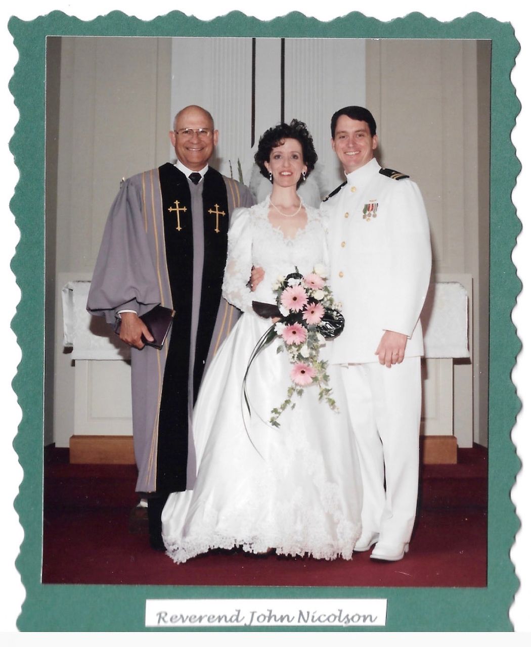 Wedding portrait: Bride and groom with officiant, church setting, bride holding bouquet, groom in white uniform.