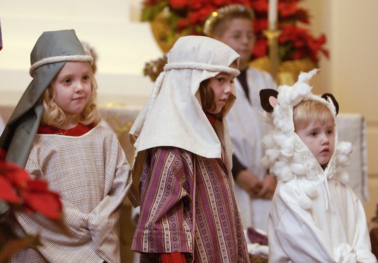 Children in costumes perform a nativity play on a stage in a church.