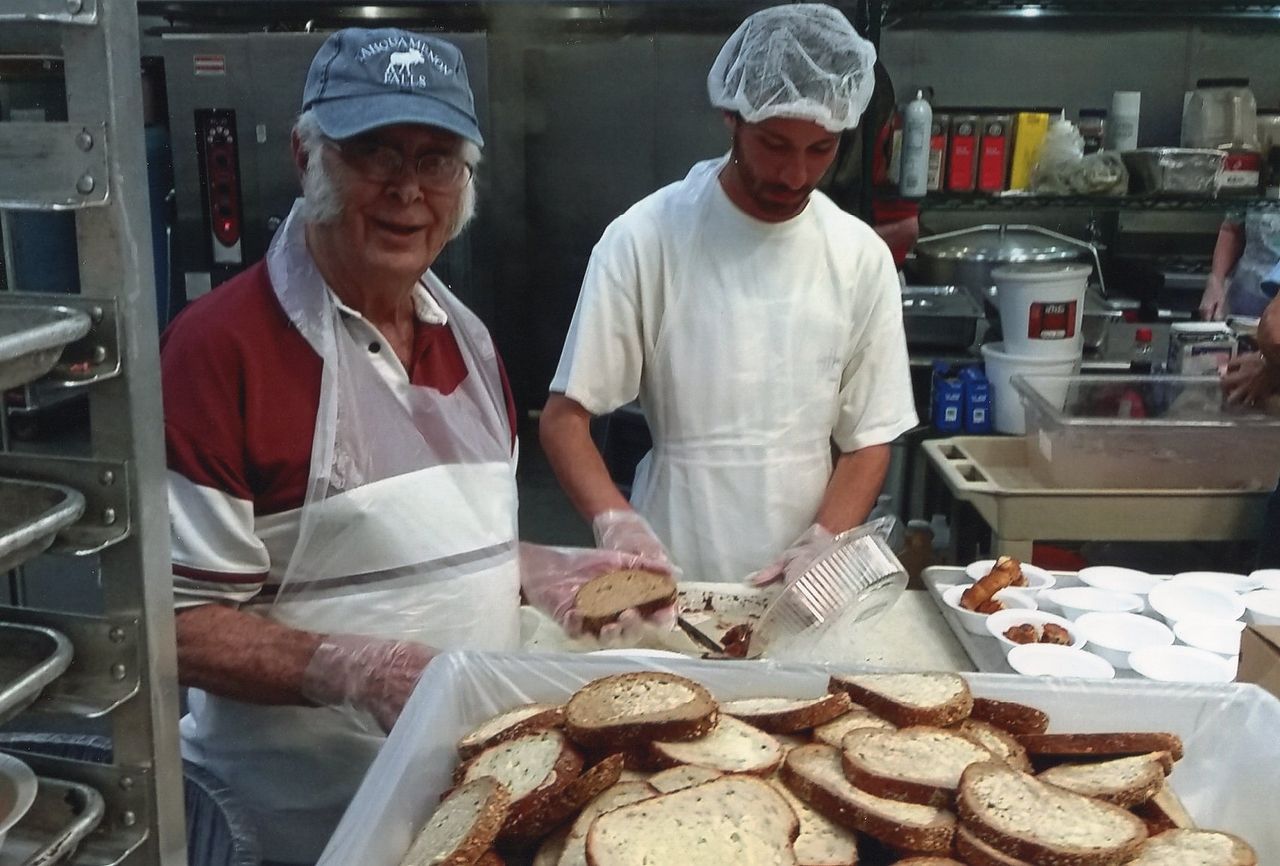 Two people preparing food in a commercial kitchen. 
