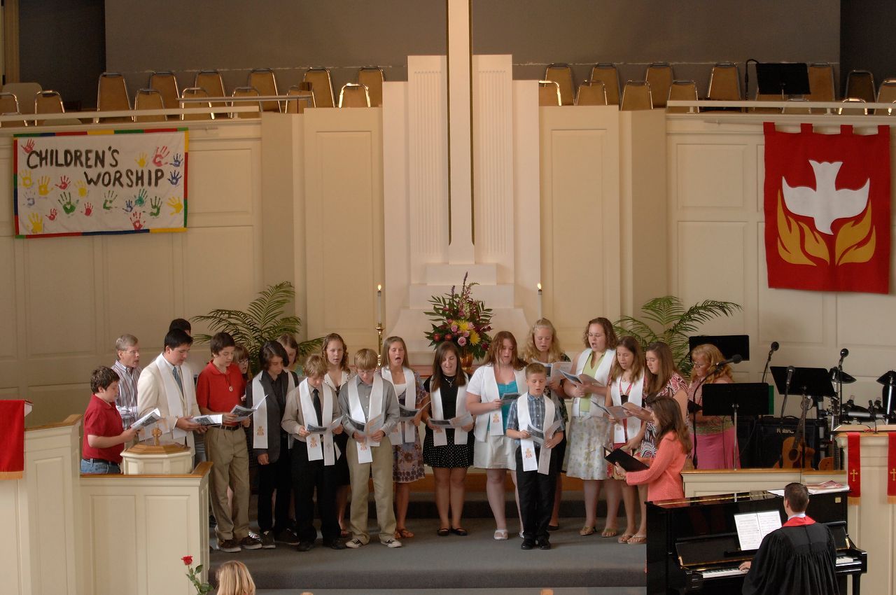 Group of people on stage in front of a cross. Banner reads 