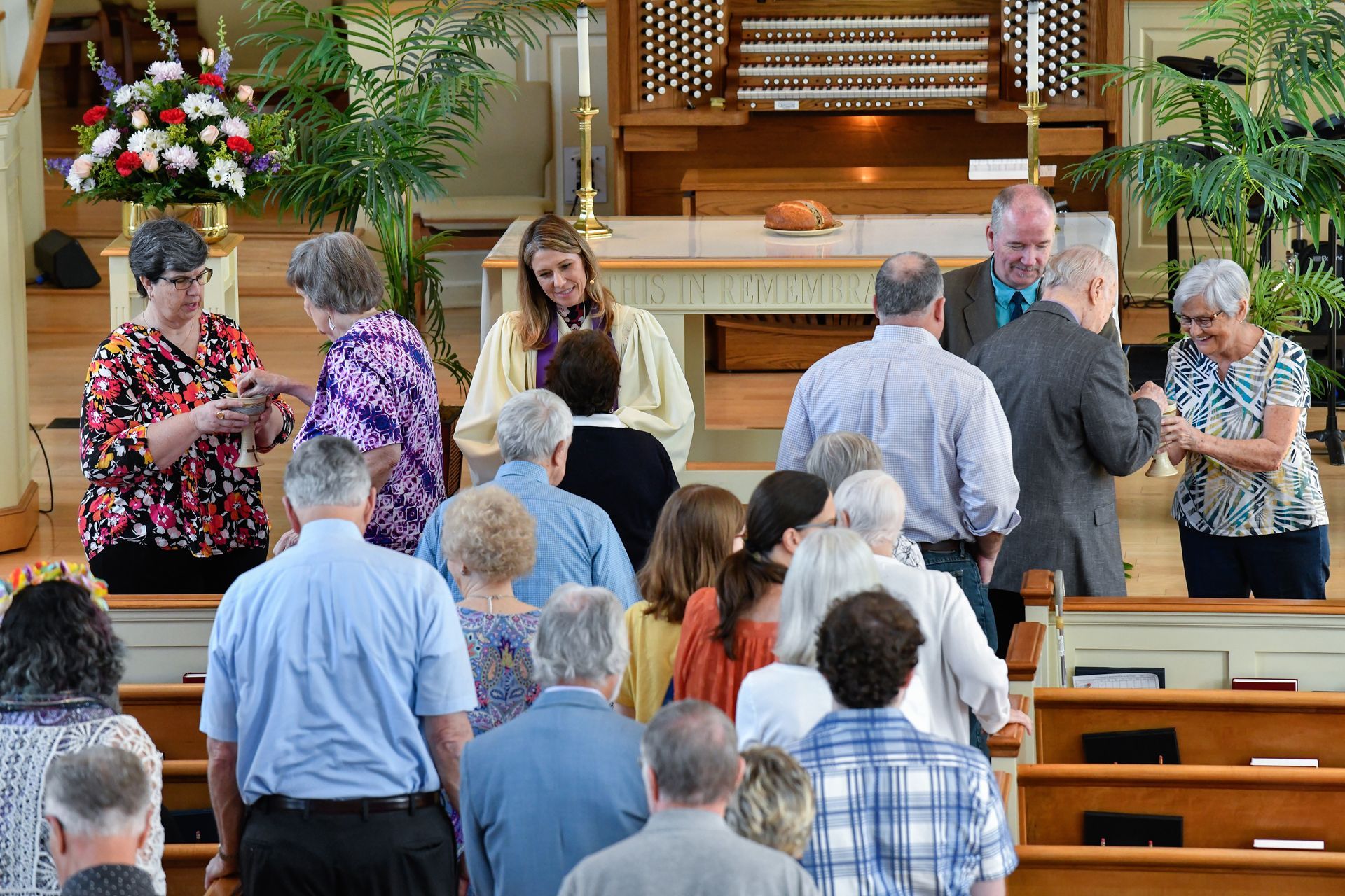 People in a church, some near an altar, others in the pews. Light streaming in.
