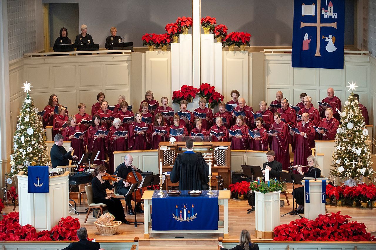 A choir and orchestra perform in a festively decorated church during a Christmas concert.