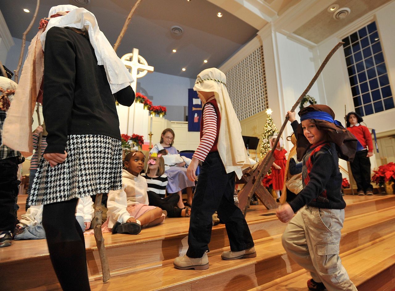 Children dressed in costumes on stage, performing play in a church.