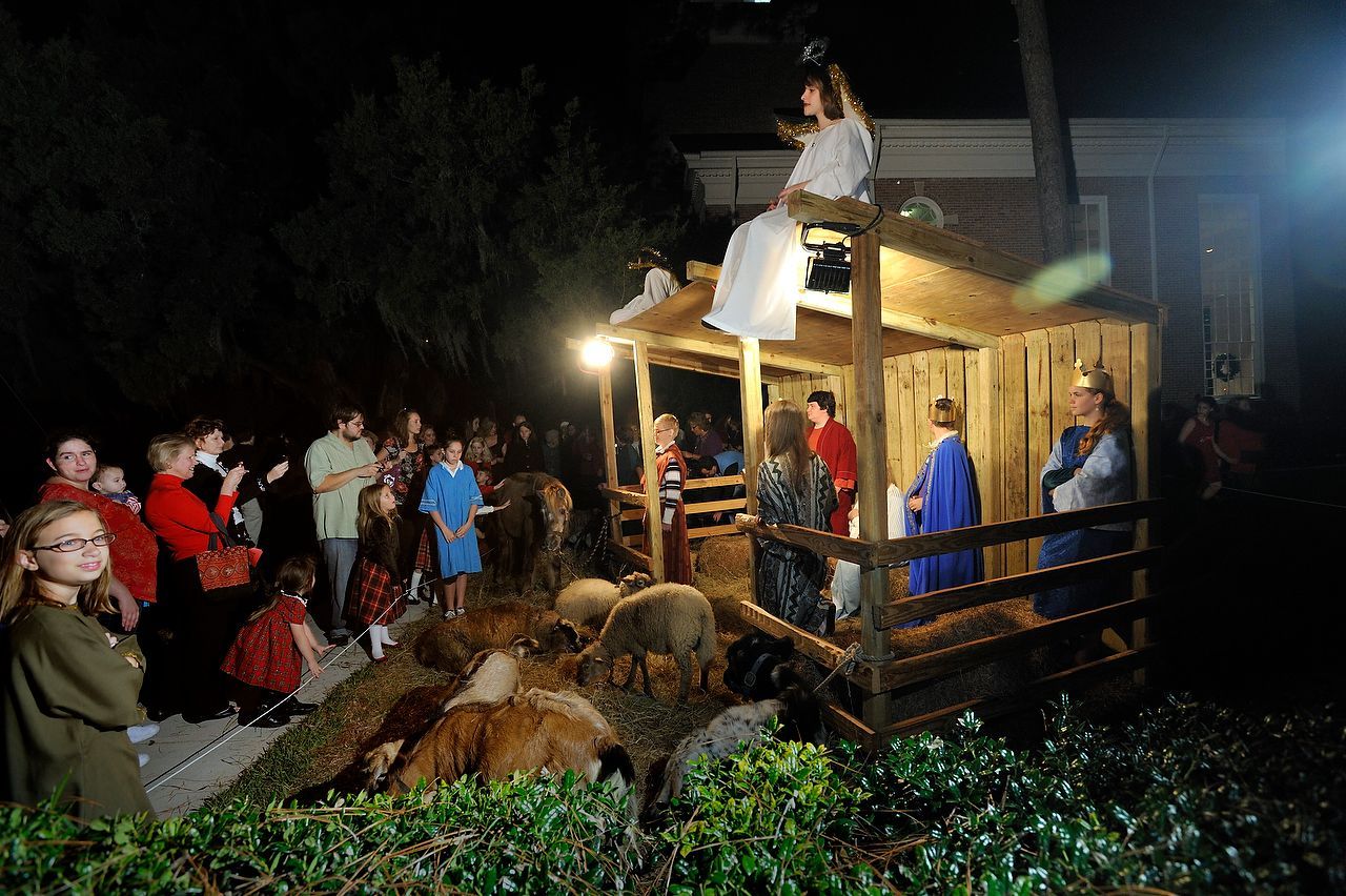 A nighttime nativity scene with people watching. Actors in costumes stand near a wooden structure.
