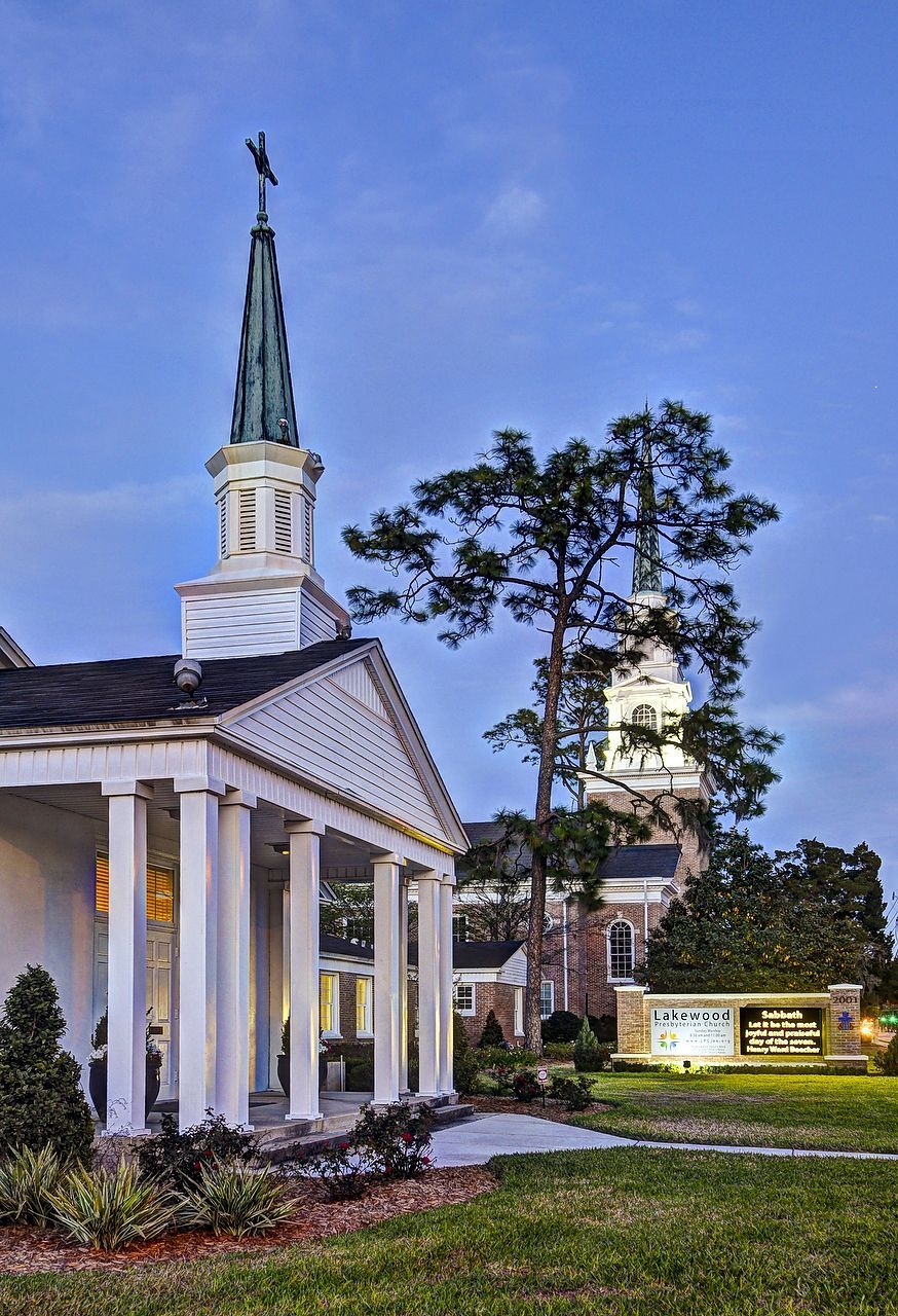 Church buildings with white pillars and steeple at dusk.