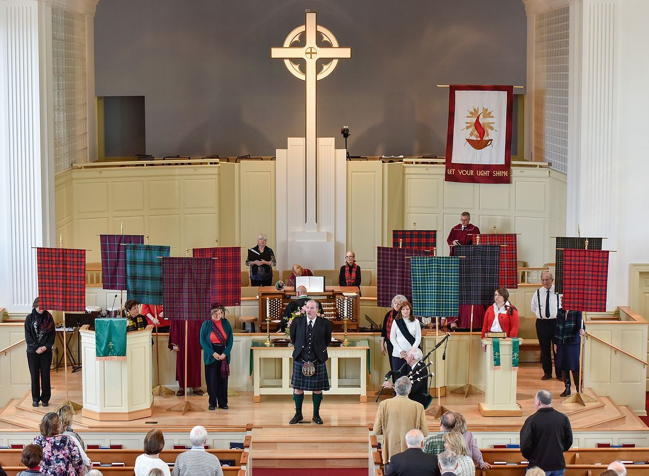 Church service featuring a man in a kilt, tartan displays, and a large cross.