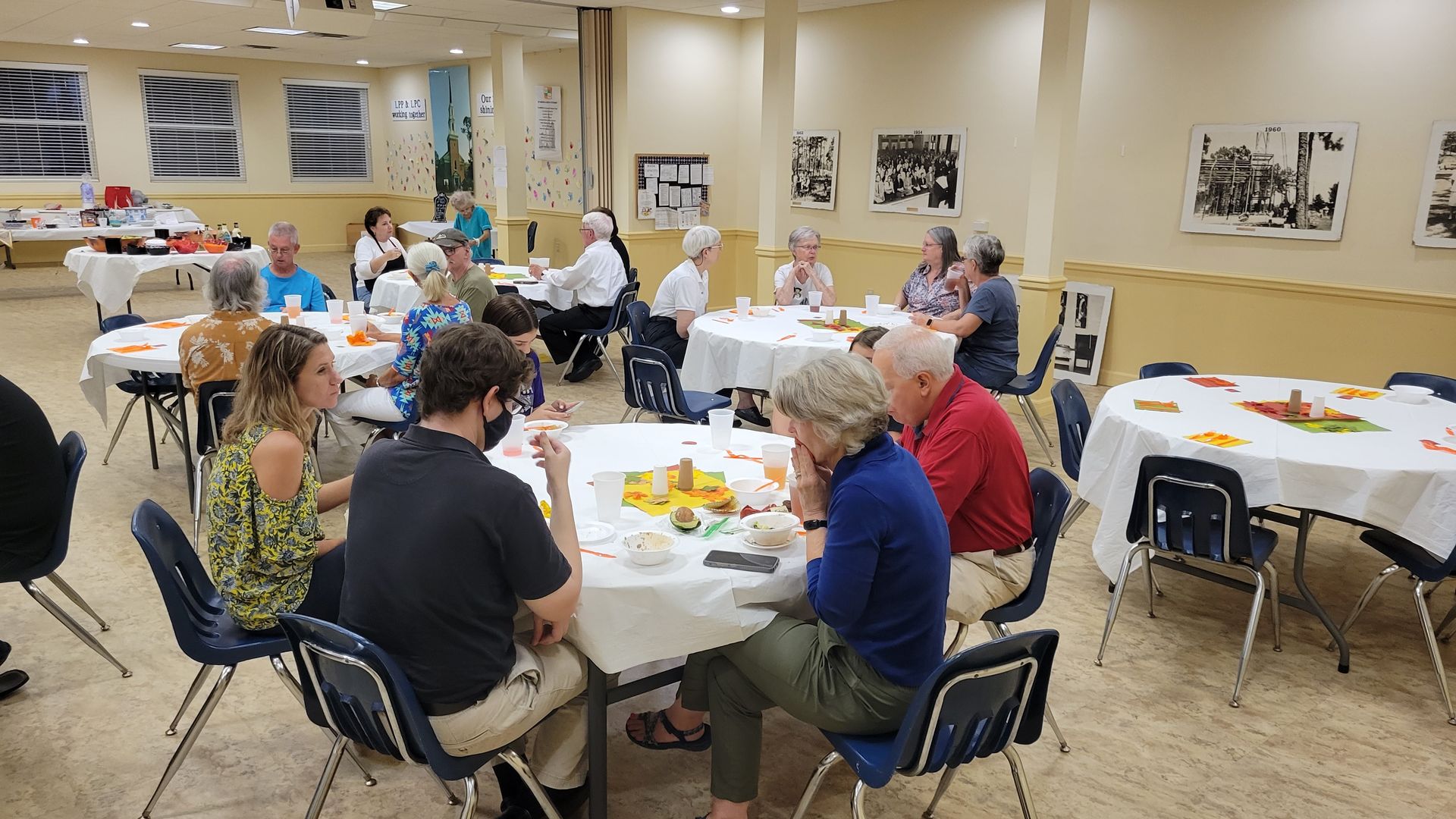 People seated at round tables in a brightly lit room, socializing during an event.