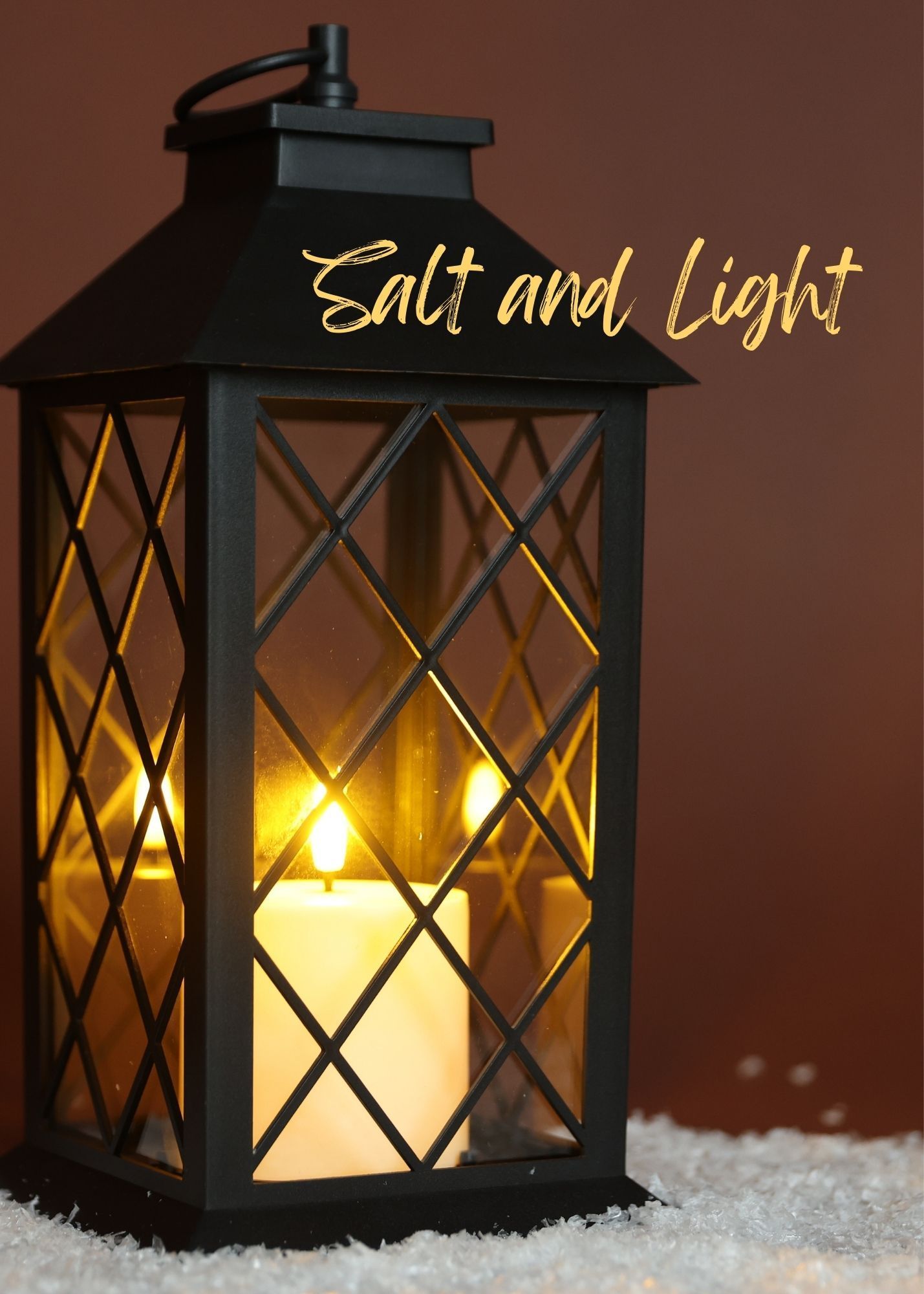 A black lantern with a glowing candle inside rests on a white snowy surface, with the text