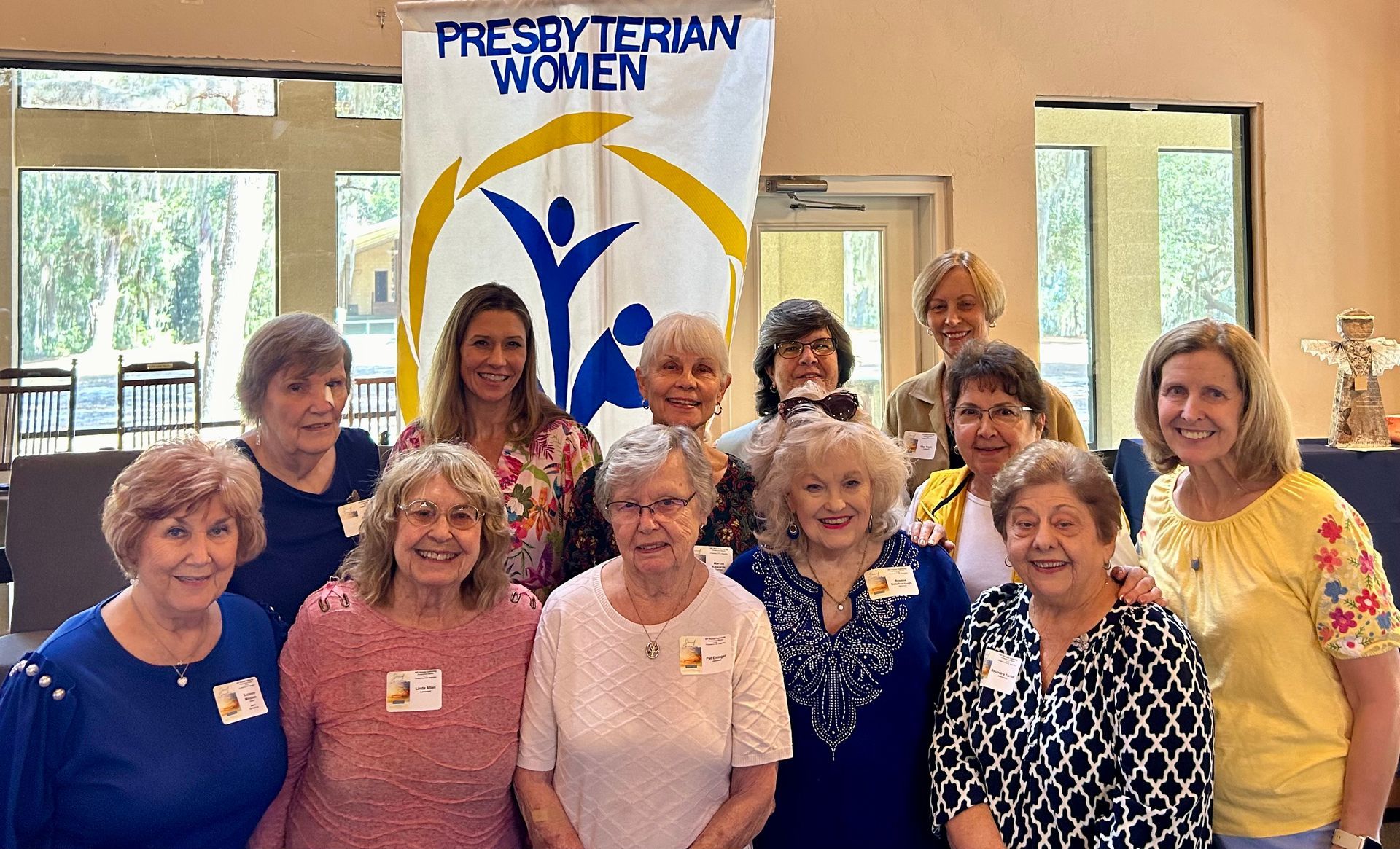 Group of Presbyterian Women posing for a photo, with banner in background.