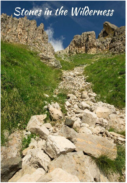 A rocky, light-colored scree slope leads up between grassy mountain hillsides under a blue sky. Text reads