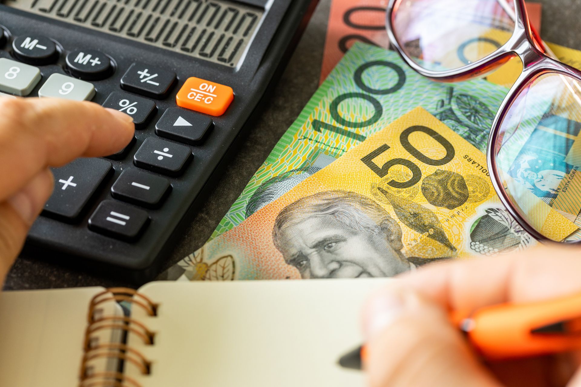A person is using a calculator next to a pile of money.