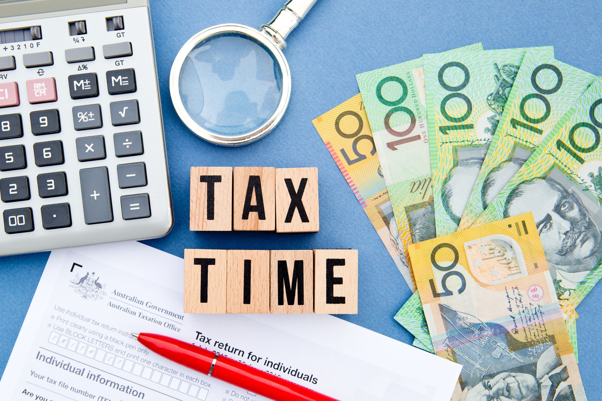 The word tax time is written on wooden blocks next to a calculator and money.