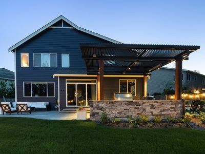The back of a house with a pergola and a stone wall