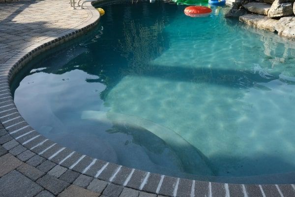 A swimming pool with a brick border and a blue water
