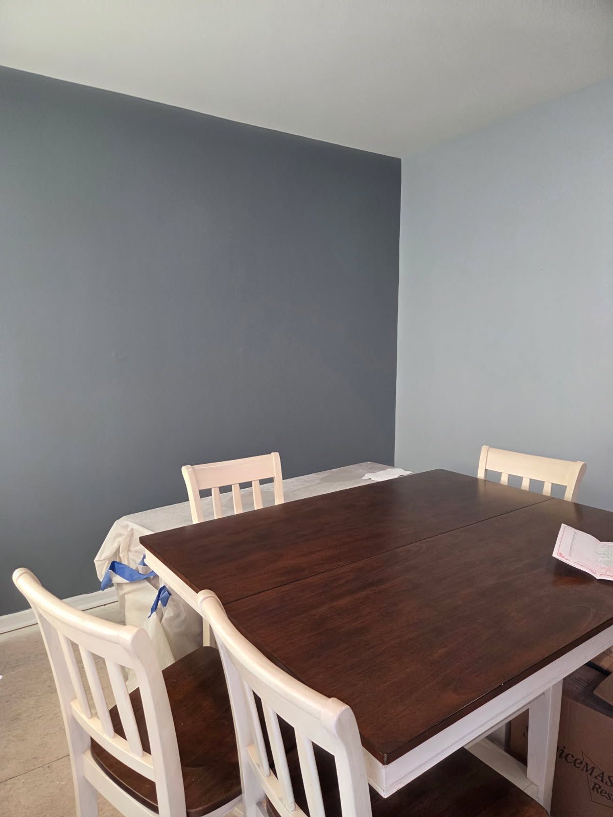 Dining table with white chairs in a room with gray walls and a dark wood tabletop