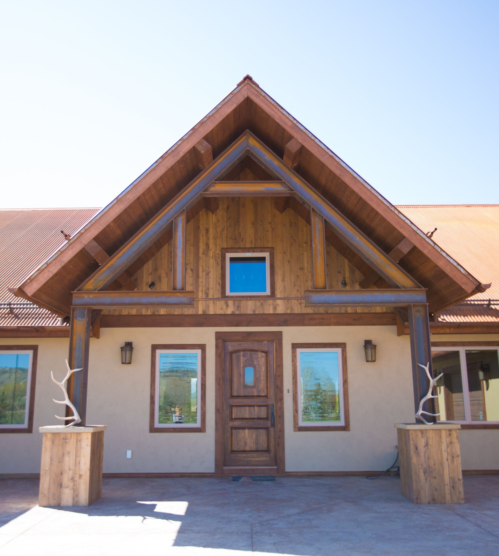 Rustic wooden entry with brown door, light brown walls, and decorative antlers on pedestals.