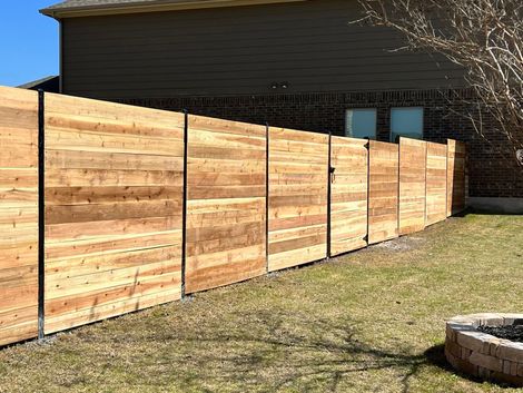 Wooden privacy fence panels along a grassy yard beside a modern building