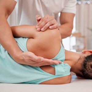 a woman is laying on a bed getting a chiropractic care.