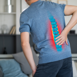 a man in a blue shirt is holding his back in pain .