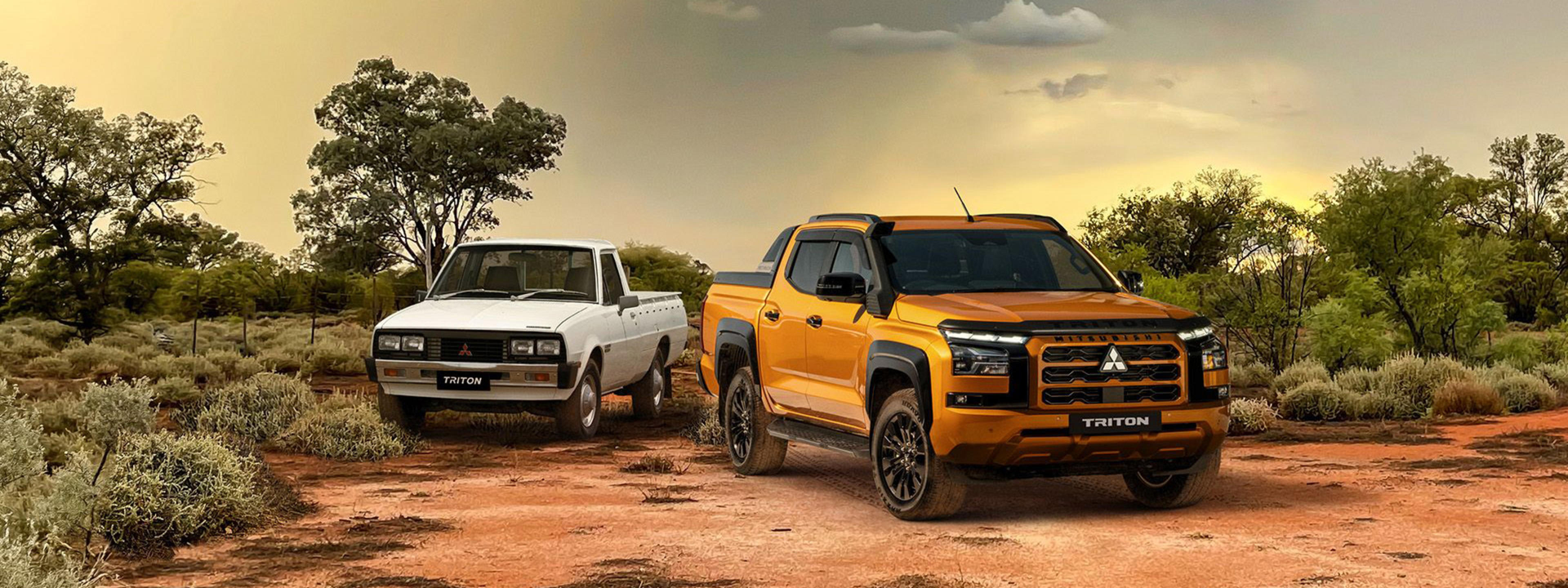 Two pickup trucks parked on a dirt road in a desert landscape with sparse vegetation.