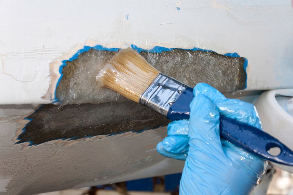 A Person Is Holding a Brush Over a Piece of Wood — Ashby Boat Builders In Buddina, QLD