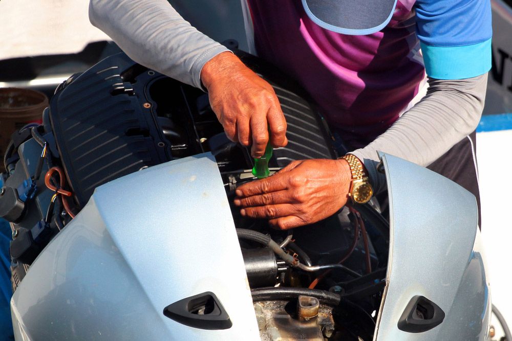 A Man Is Working on A Boat Engine with A Wrench — Ashby Boat Builders In Buddina, QLD