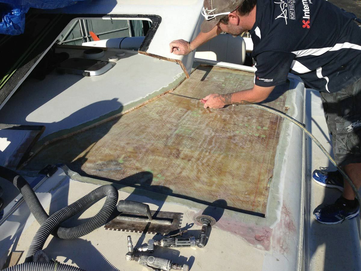 A Man Wearing a Shirt that Says ' Yacht Club ' on It Is Working on A Boat — Ashby Boat Builders In Buddina, QLD