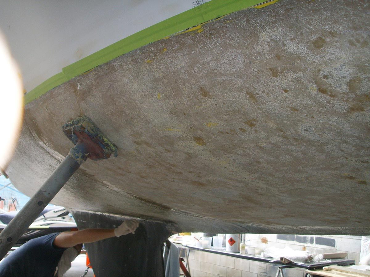 A Person Is Cleaning the Bottom of A Boat with A Brush — Ashby Boat Builders In Buddina, QLD