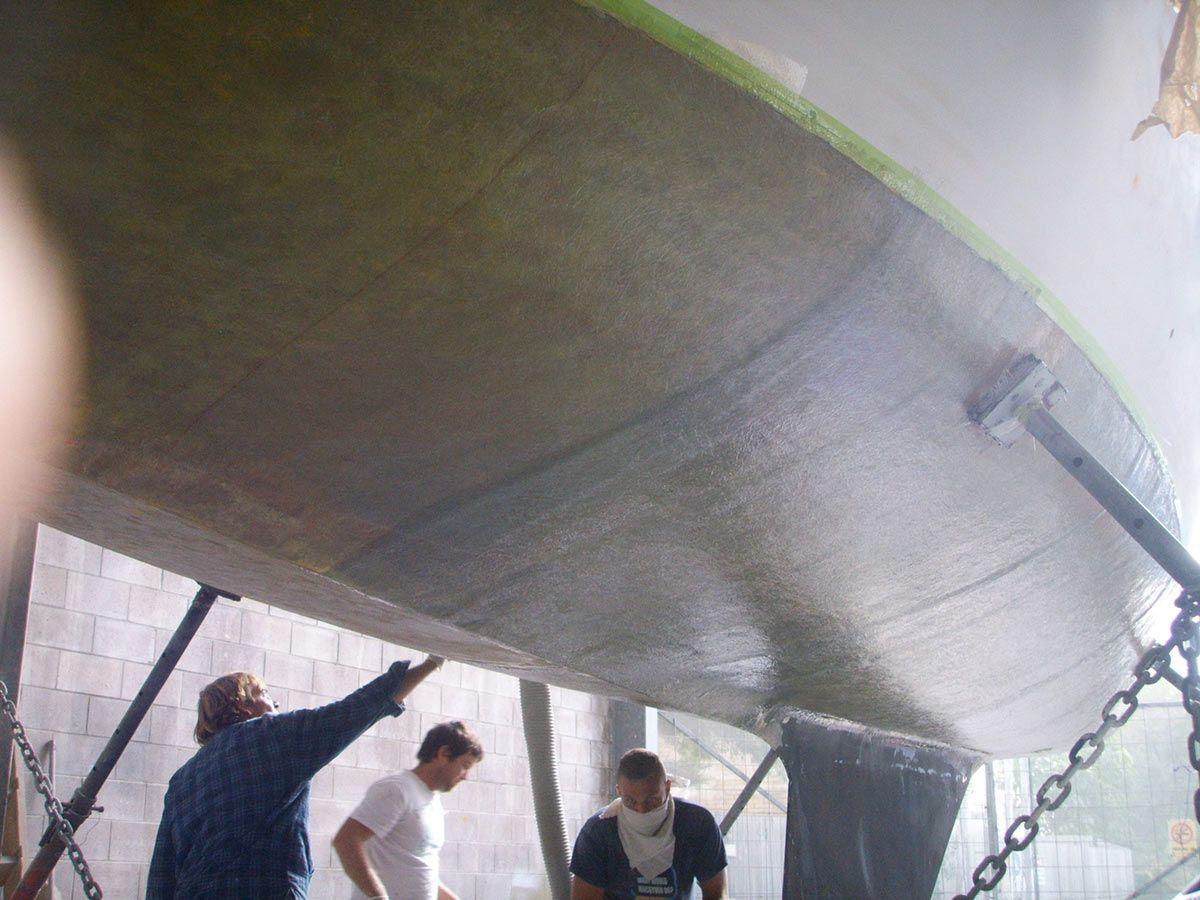 A Group of Men Are Working on A Boat in A Garage — Ashby Boat Builders In Buddina, QLD