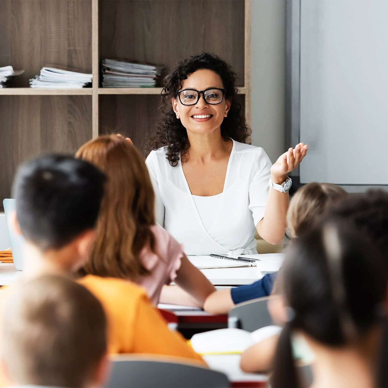 A teacher is giving a presentation to a group of students in a classroom.