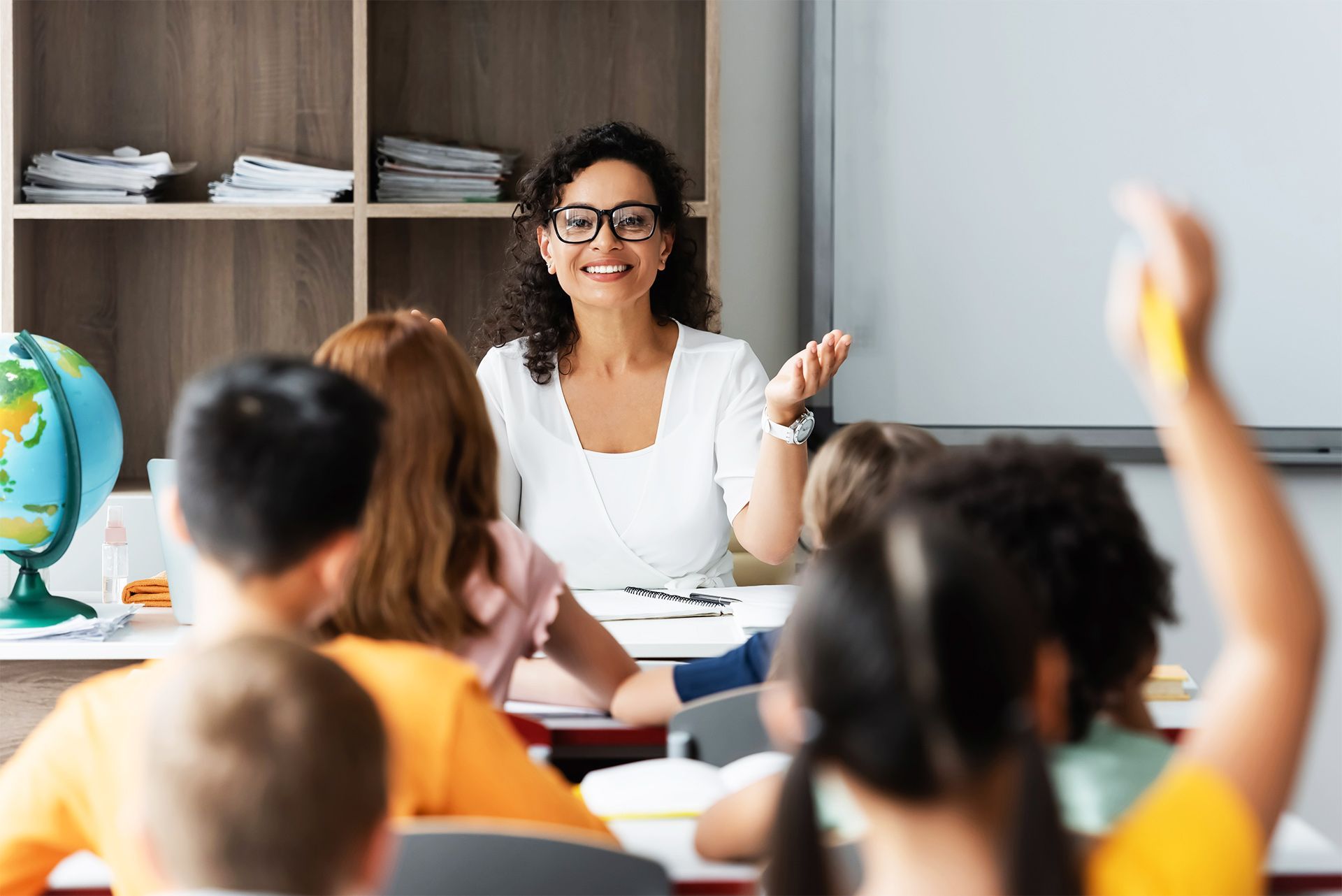 A teacher is asking a question to her students in a classroom.
