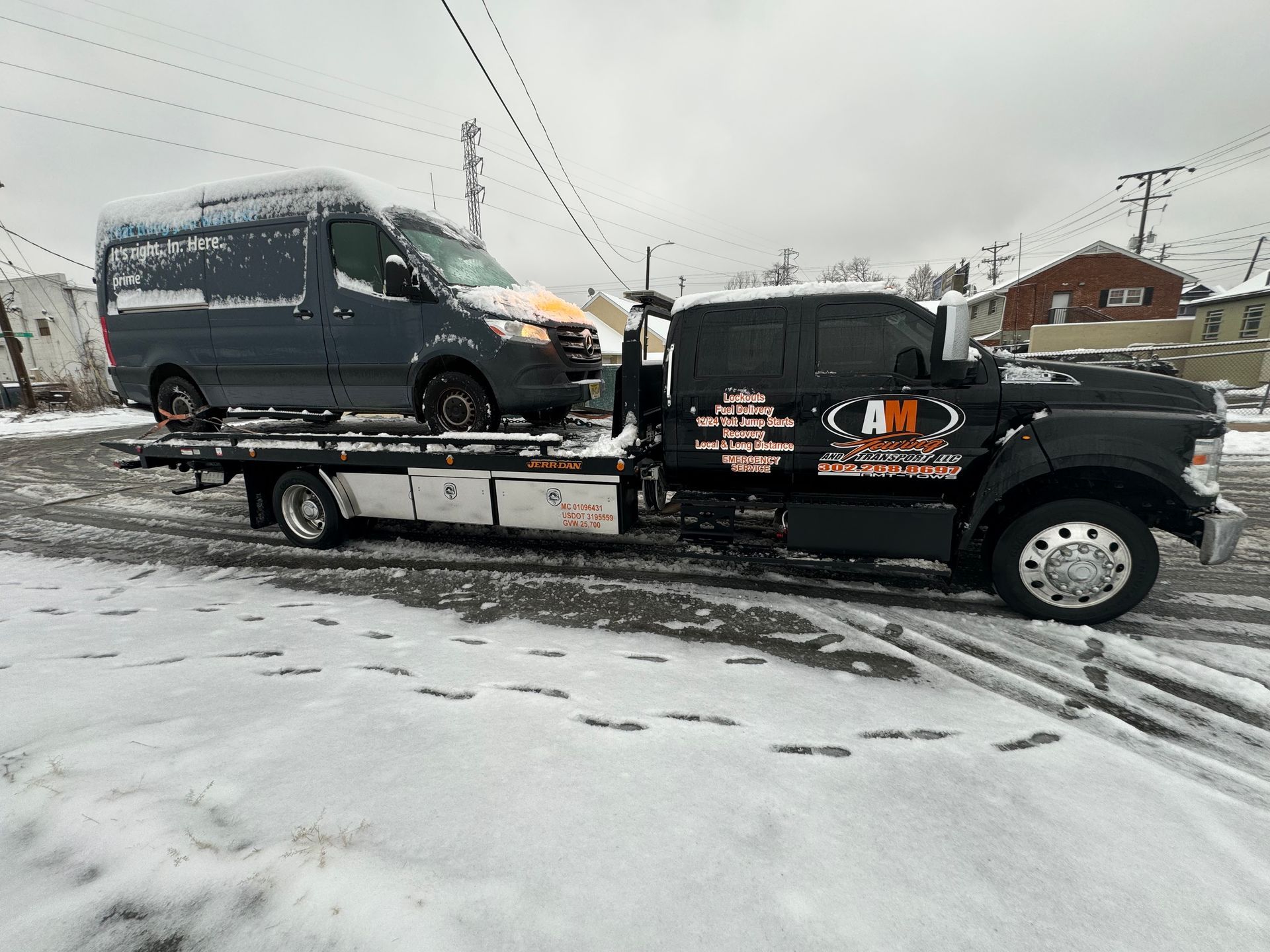 Tow truck transporting a gray van in a snowy area.