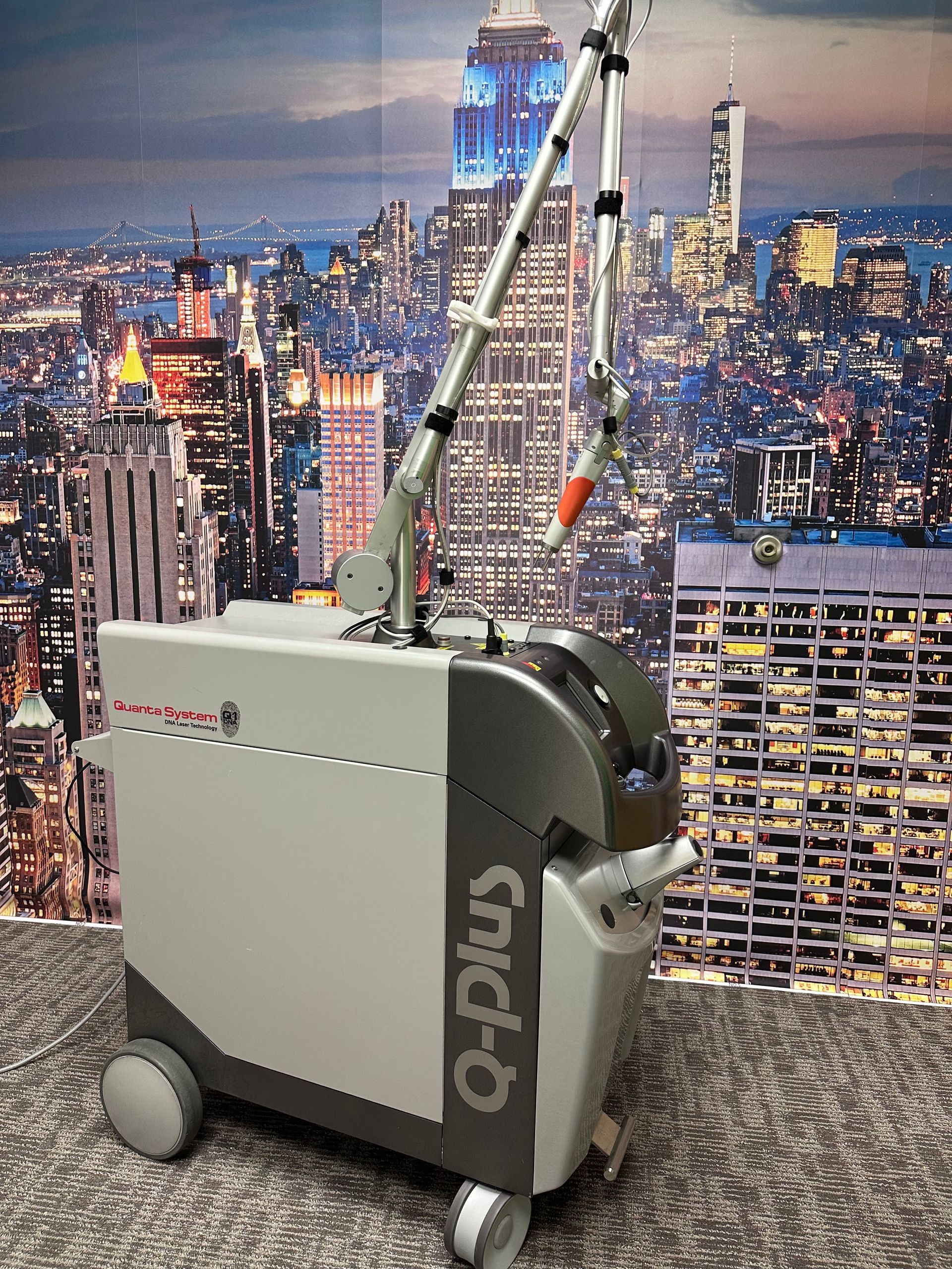 Laser device with articulated arm, in a room with a cityscape backdrop.