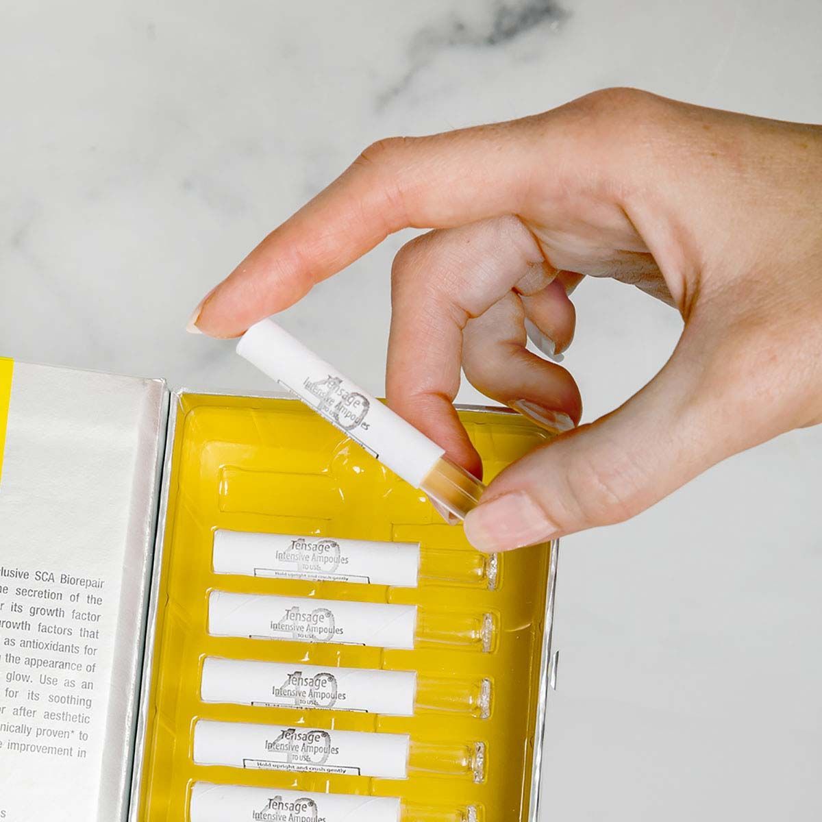 Hand taking a white cigarette filter from a yellow tray in a white box.