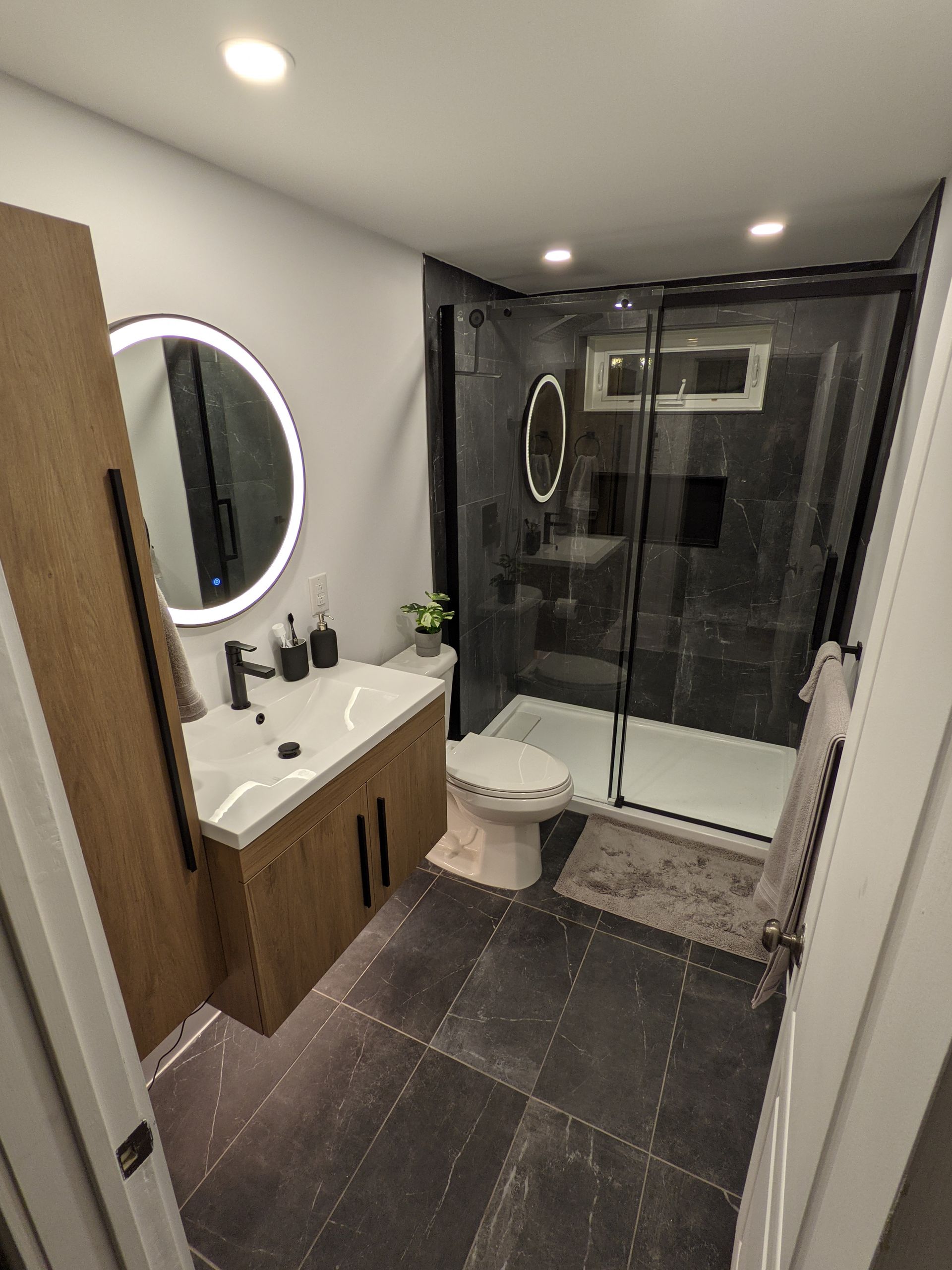 Une salle de bain avec lavabo, WC, douche et miroir.