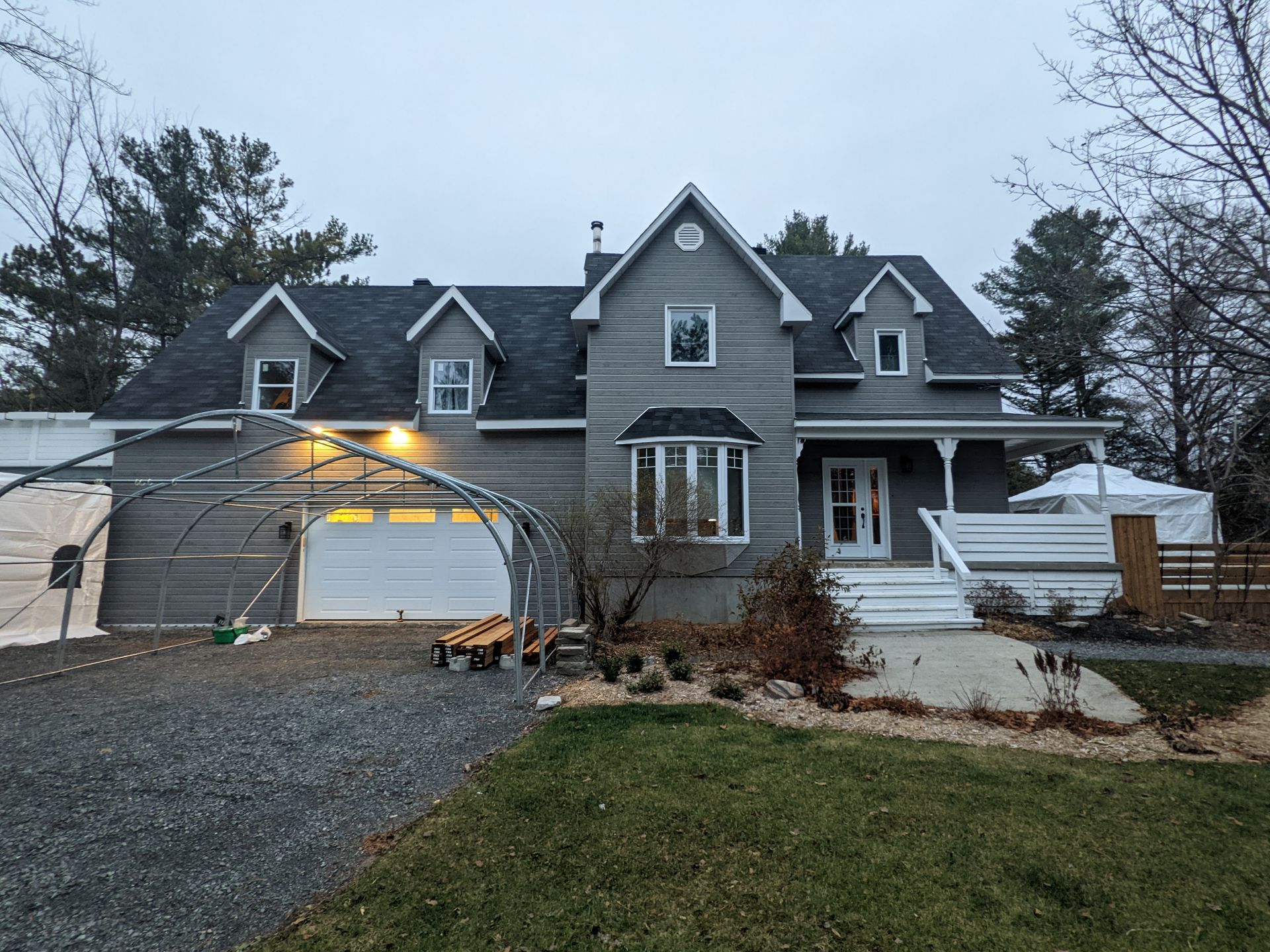 Une grande maison avec un garage et une tente devant.