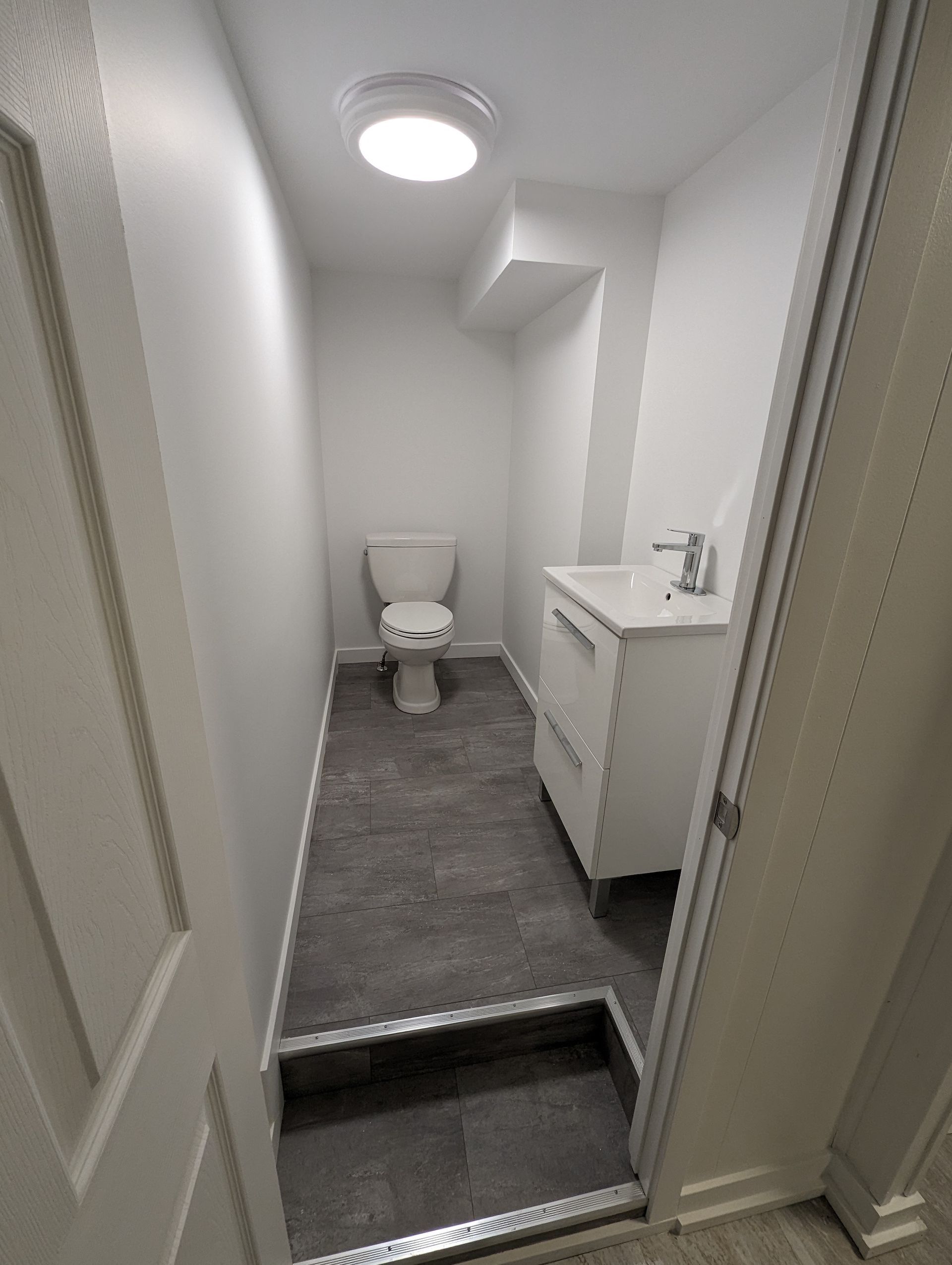 Une salle de bain avec WC, lavabo et lumière au plafond.
