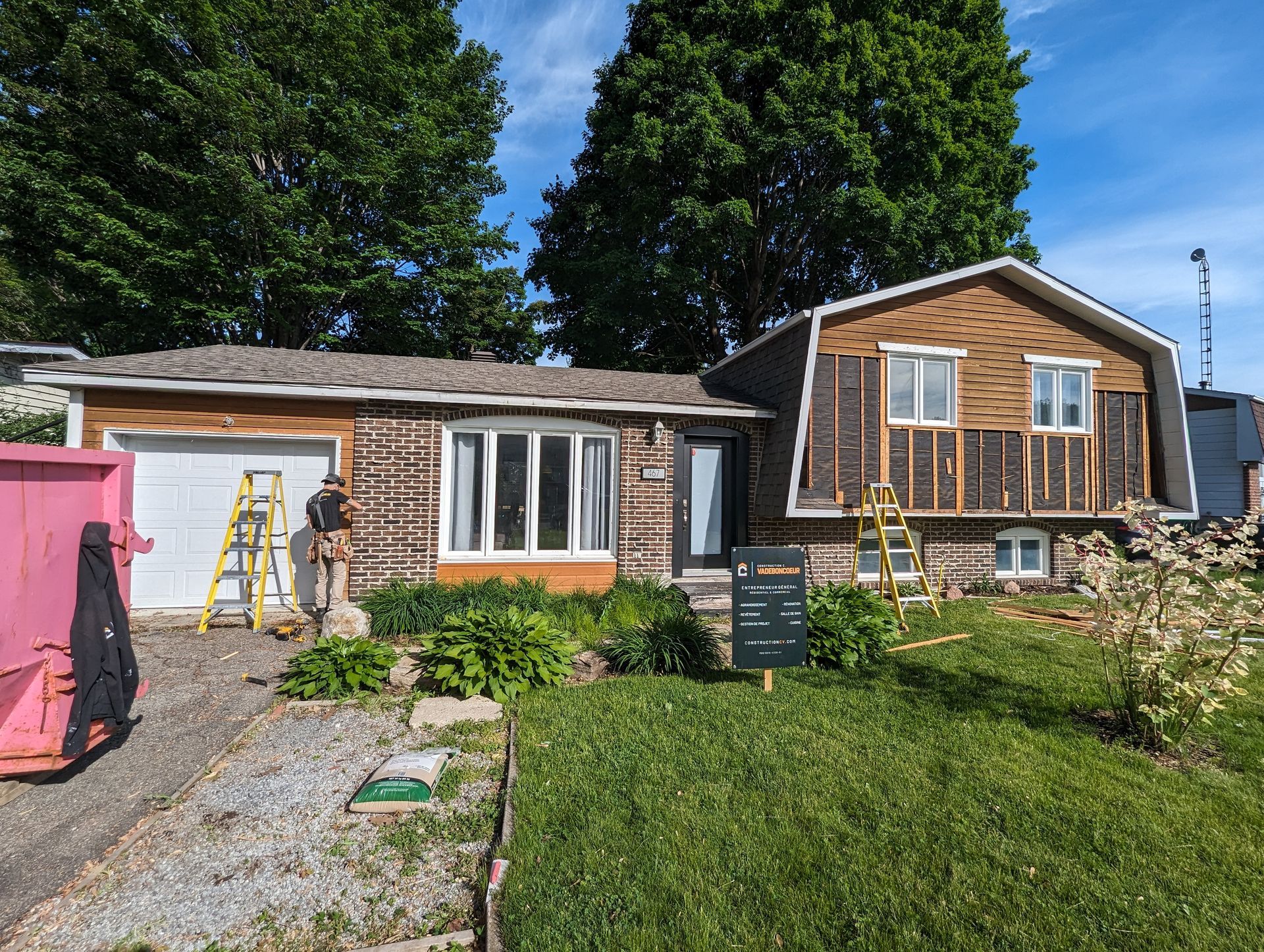 Une maison est en cours de rénovation avec un panneau devant elle.
