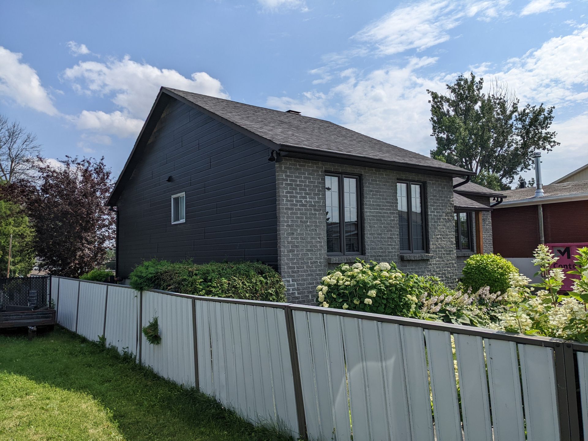 Une petite maison avec une clôture blanche devant elle.