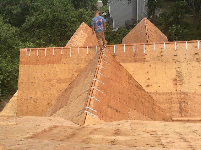 Construction worker on plywood roof framework, building a house. Sunny day, exterior shot.