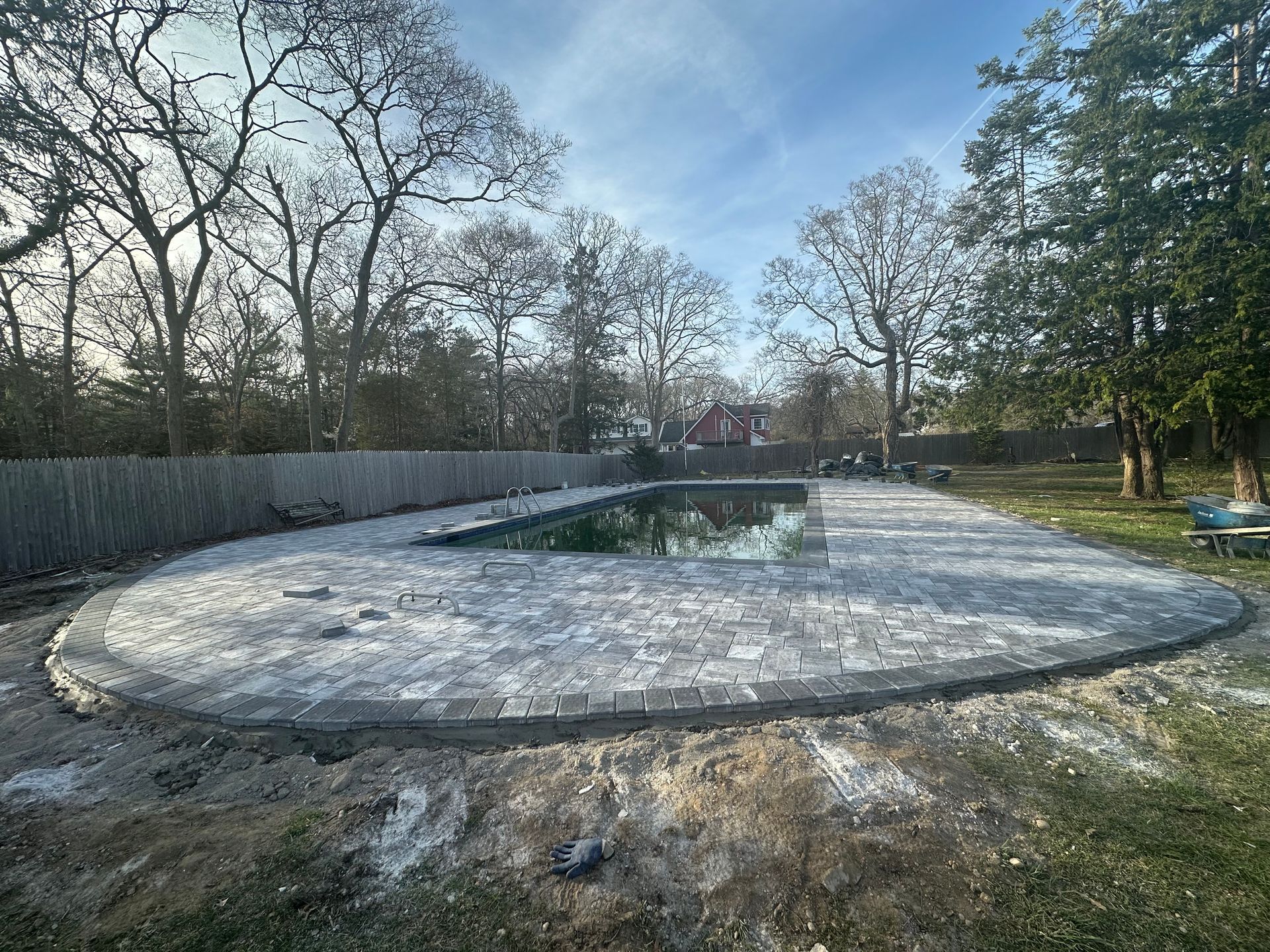 Pool with gray stone border, green water, and surrounding trees.